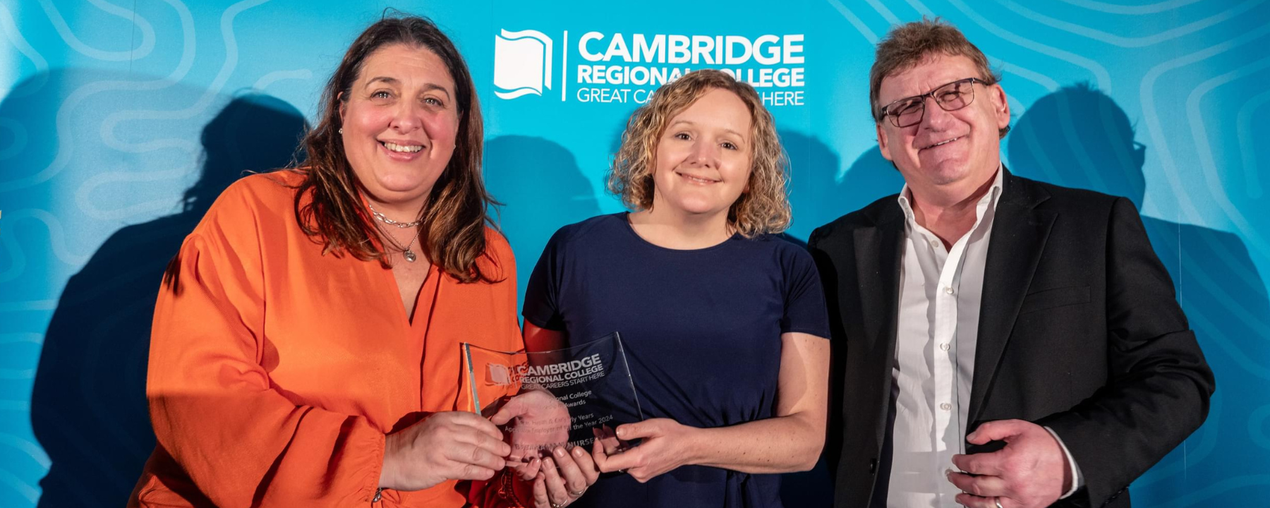 Two Nursery representatives receive an award from a third person.