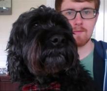 The faces of a man with glasses and a black dog